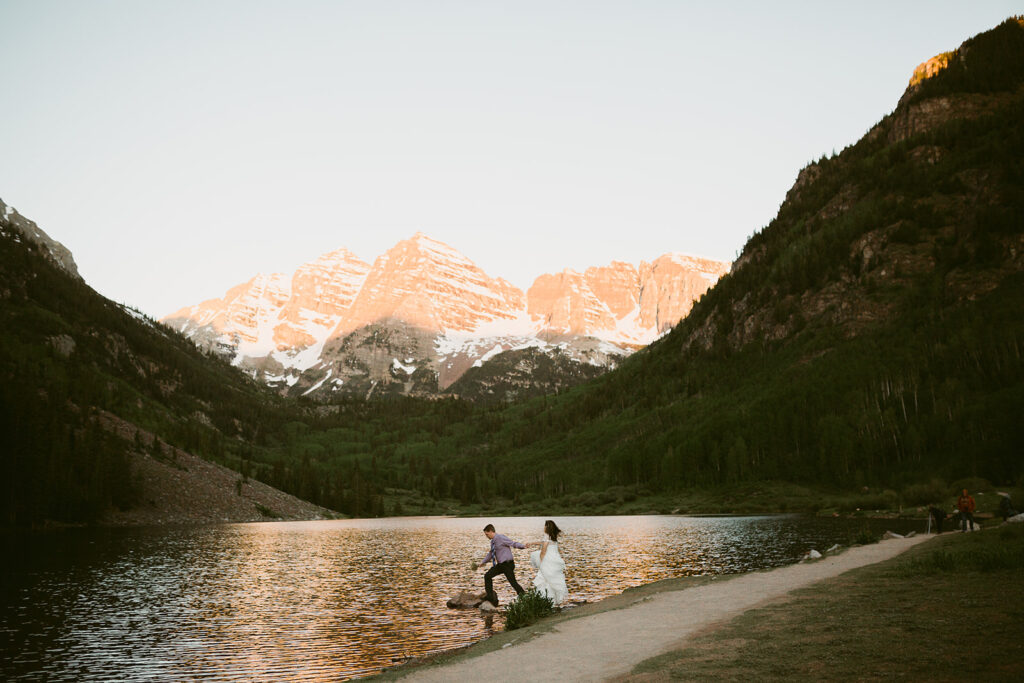 Couple walking hand in hand beneath the towering Maroon Bells mountains