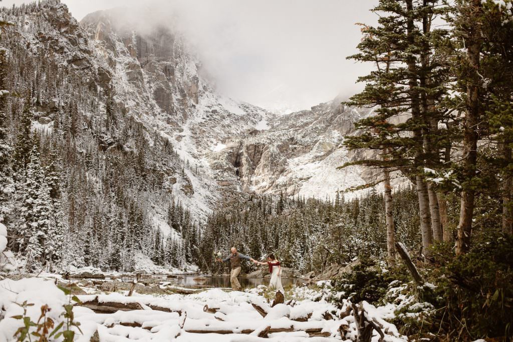 "Dream Lake hiking elopement in Rocky Mountain National Park, Colorado featuring an adventurous couple exploring the snowy alpine landscape — photographed by Justyna E Butler, Colorado adventure elopement photographer"