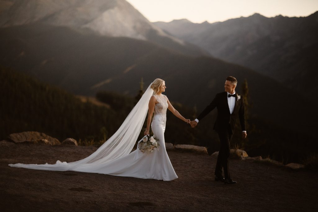 Newlyweds embracing outside The Little Nell surrounded by Aspen mountains