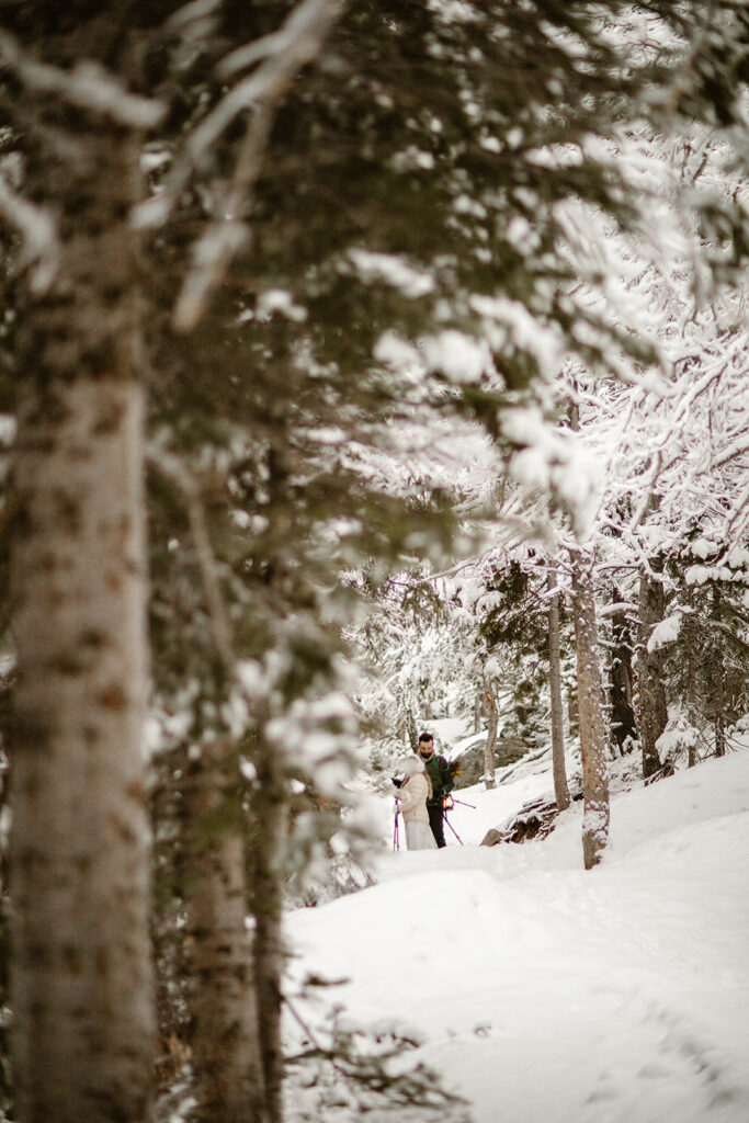 Newlyweds exploring a snow-covered mountain trail at sunrise