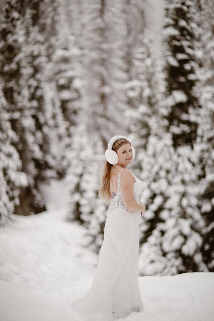Bride smiling beneath snow-covered pine trees in Rocky Mountain National Park