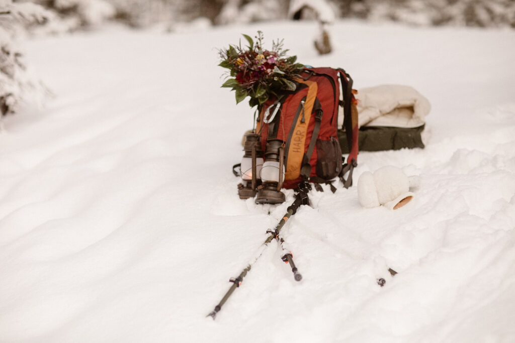 Bridal bouquet resting on fresh June snow in Colorado attached to the hiking backpack