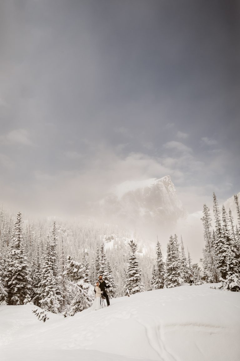 “Adventurous winter Colorado elopement with bride and groom snowshoeing through a snowy mountain forest, captured by elopement photographer.”
