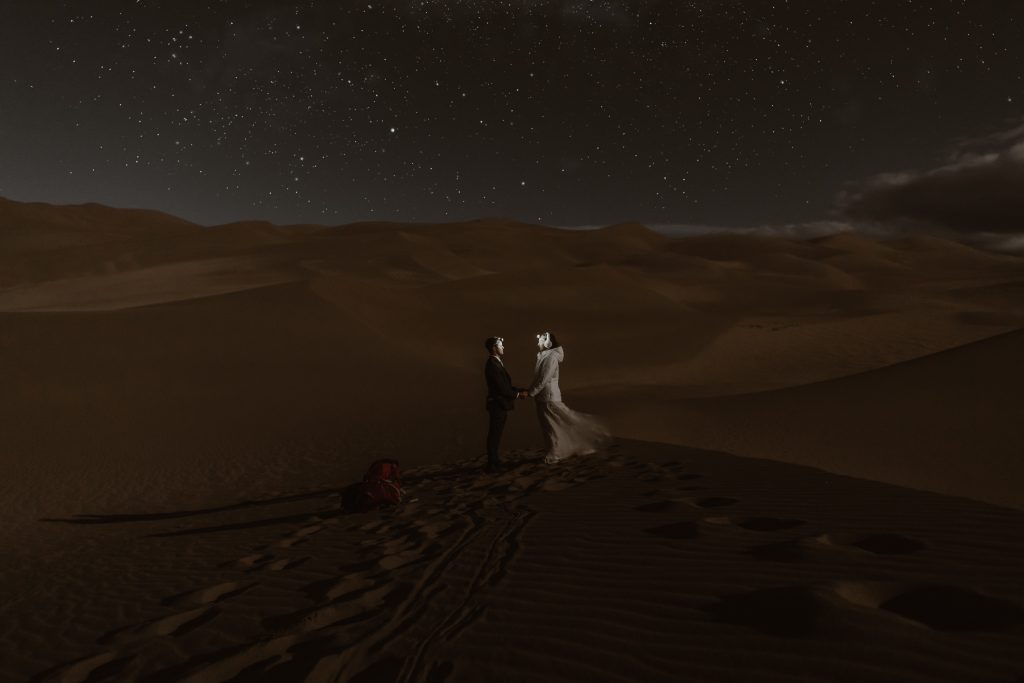Great Sand Dunes National park Elopement Colorado "Upon entering the sand field we basked in the late season glow of the cottonwoods before feeling the last of the sun’s warmth across the flat sand. We danced in the wind and climbed up the dunefield to say our vows at dusk. The moment was intimate and uninhibited (and a little windswept!); afterwards Justyna celebrated with us. Shortly thereafter, the almost-full moon rose and the sand collected its pale light. We remained while the stars appeared. We then retired back to the moon-and-lantern-lit hot tub to hold each other and watch the clouds race across the night sky. ” Colorado Elopement Adventure bride