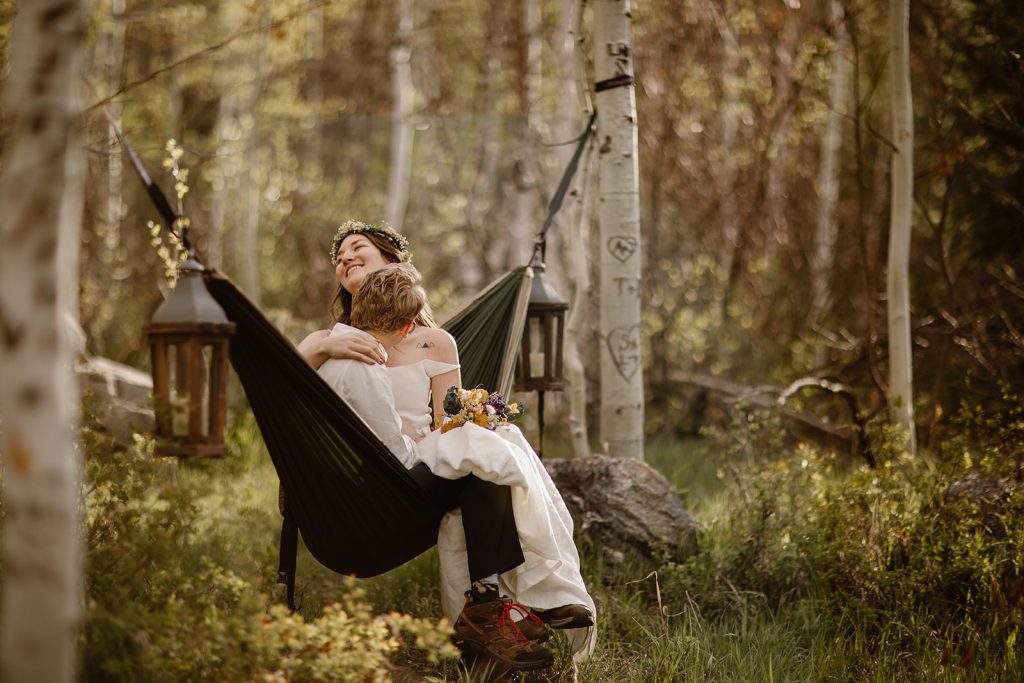 Bride and groom sitting in a hammock in the Colorado woods during intimate forest elopement