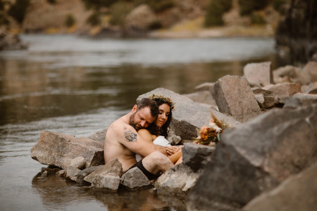 Couple unwinding in a natural mineral hot spring surrounded by Colorado mountains.