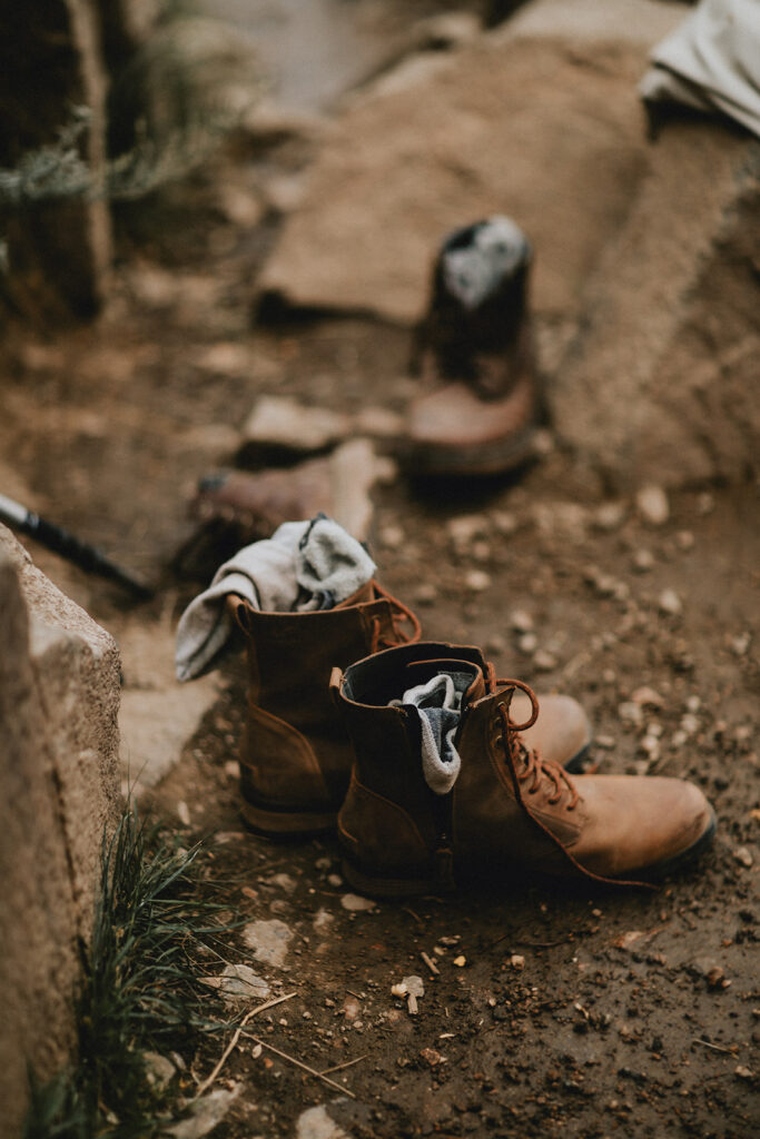 Hiking boots and socks as details while a couple soaks in a Colorado hot spring after their Breckenridge elopement.