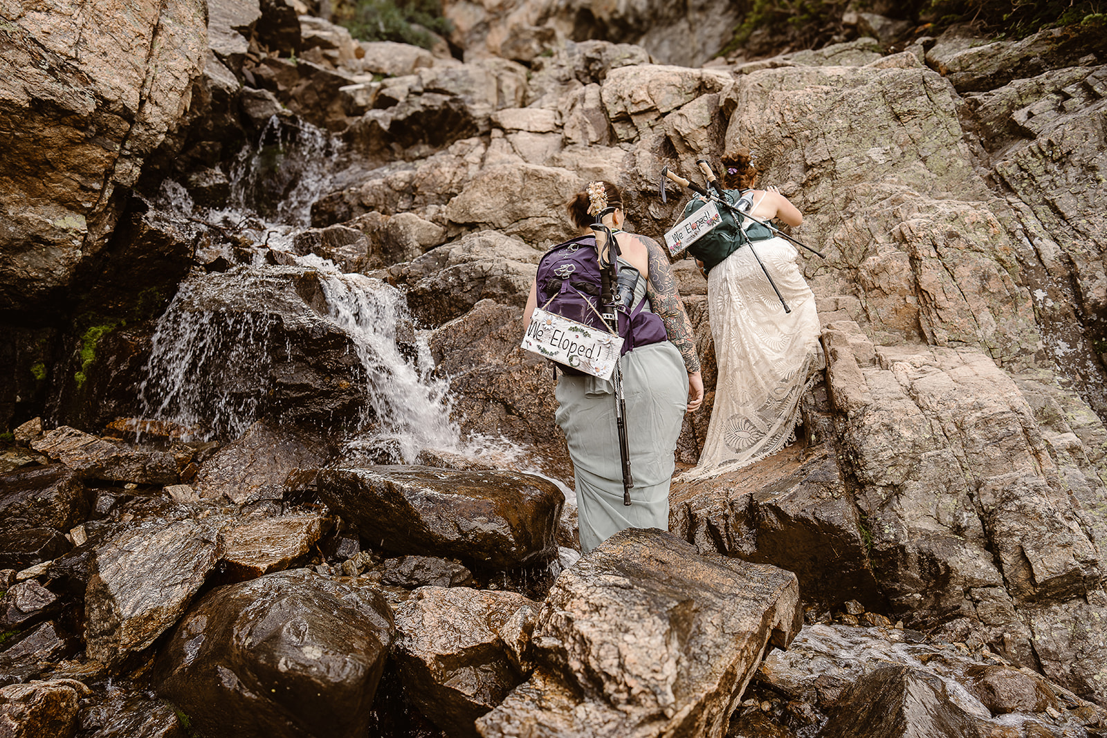 Couple hiking beside Colorado waterfall during adventure elopement at Sky Pond, Rocky Mountain National Park 