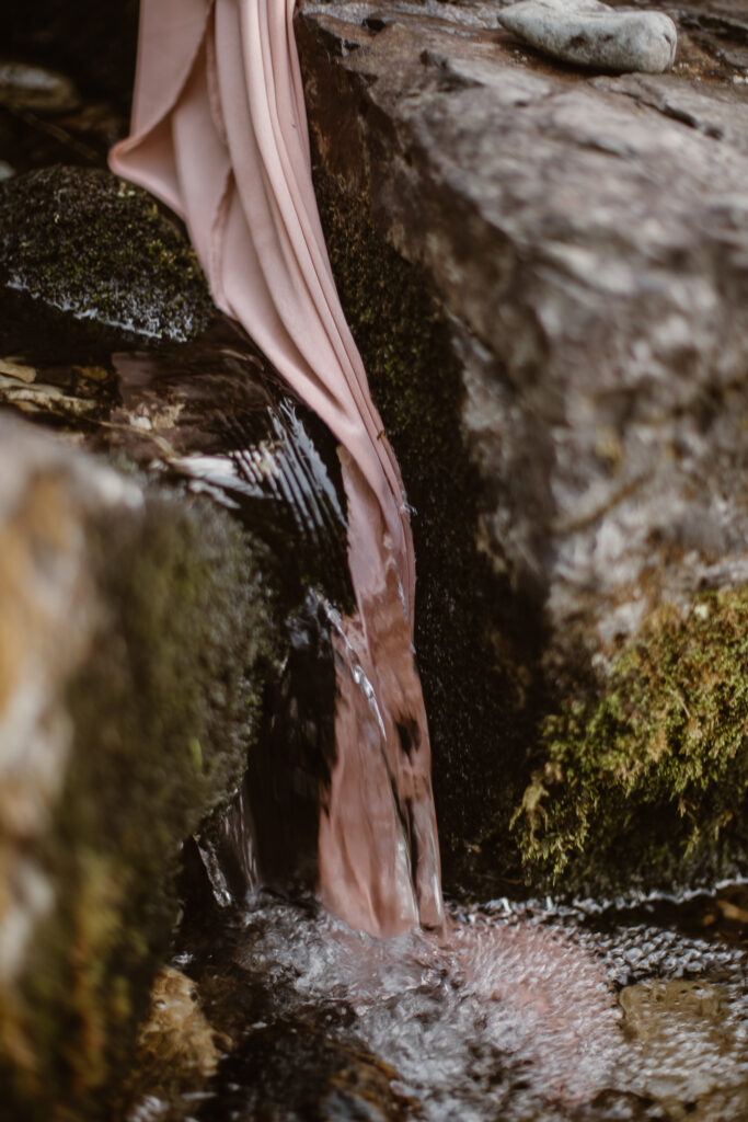 Crystal-clear mountain stream flowing beneath a secluded waterfall in Colorado.