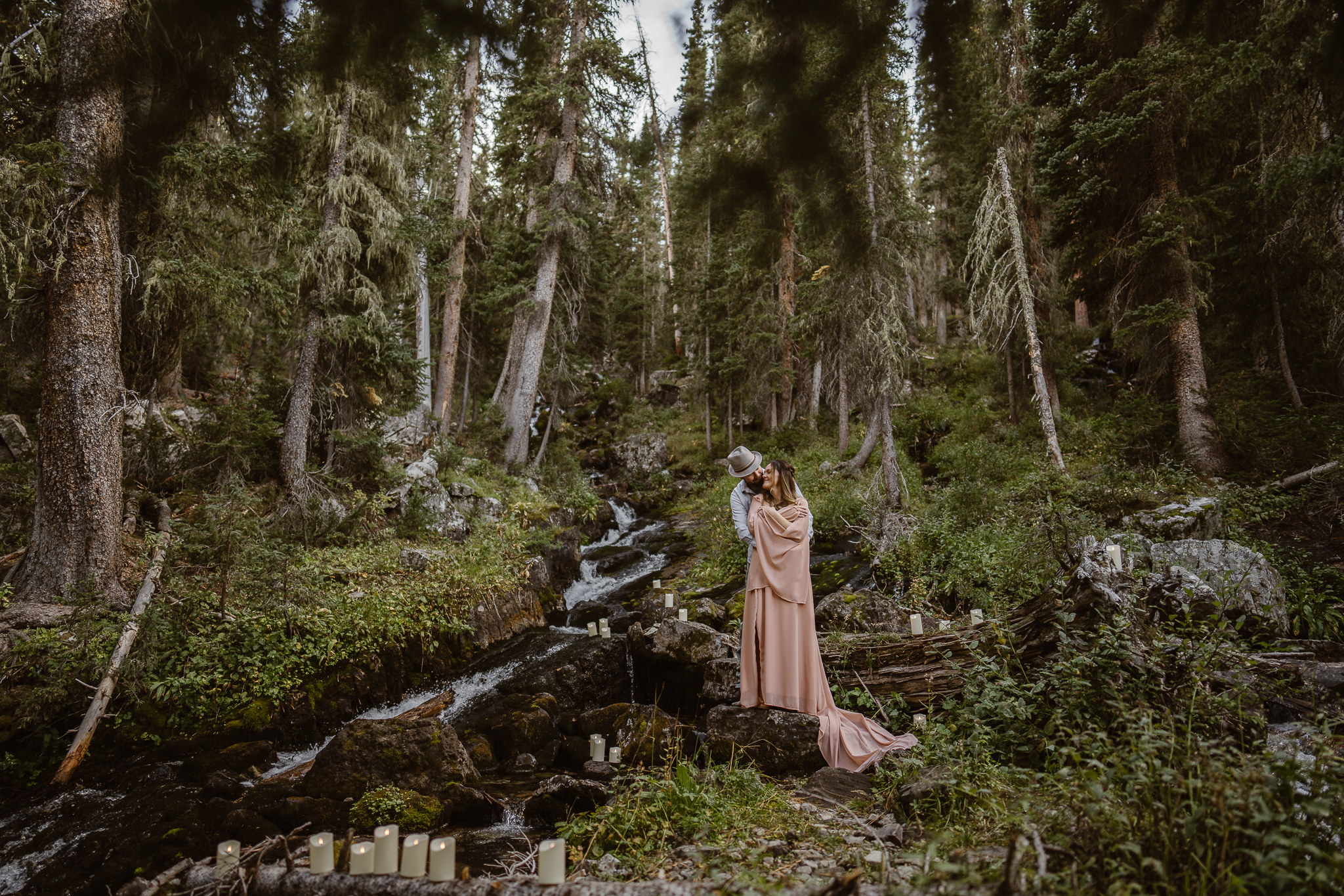 Bride and groom sharing a quiet moment beside a moss-covered waterfall in Colorado.
